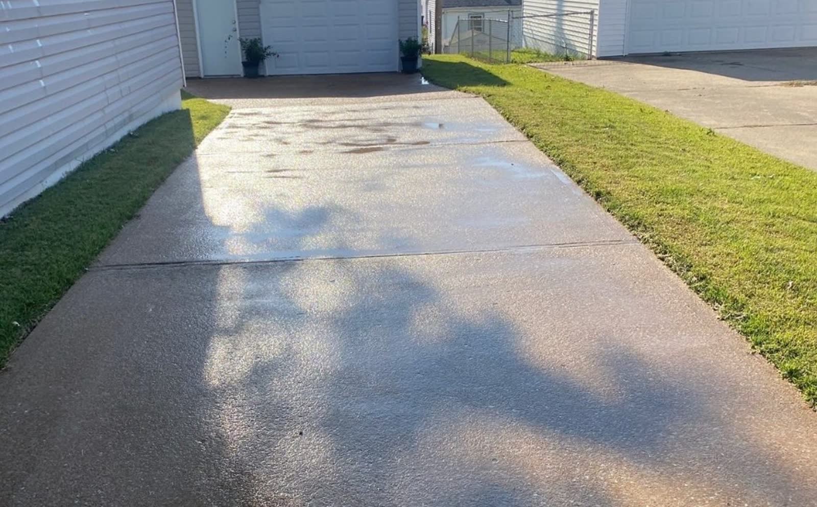 Freshly cleaned concrete driveway running back to a detached garage at a St. Louis County home